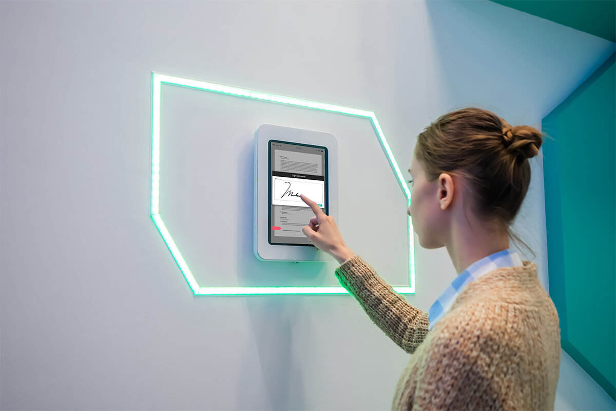 Woman signing a document on a kiosk